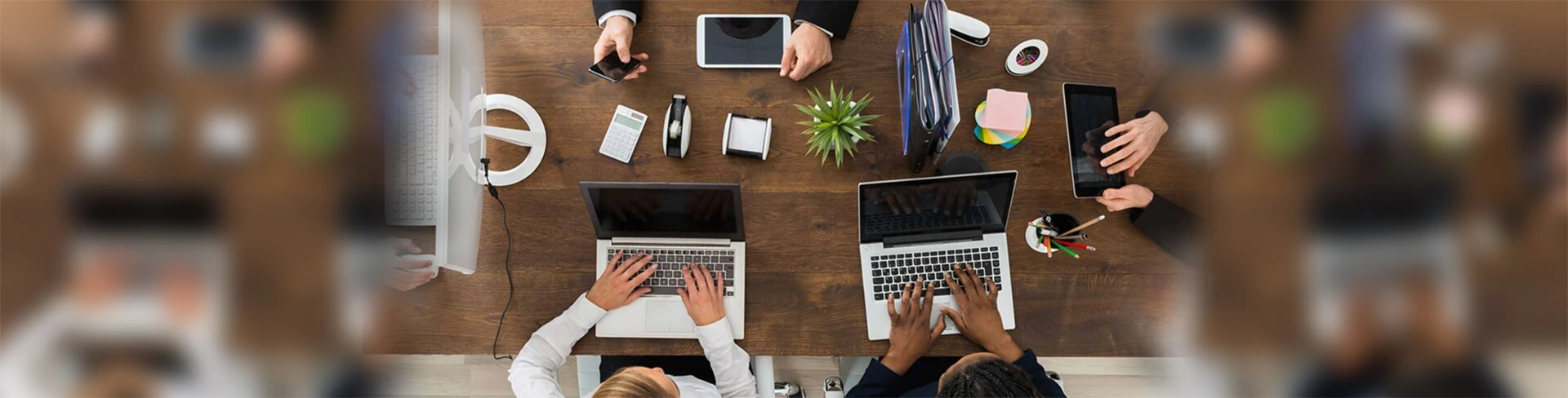 Grupo de colaboradores reunidos em uma mesa com seus materiais de trabalho