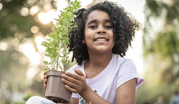 Criança segurando um vaso com uma planta