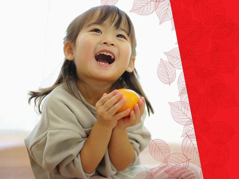 Criança sorrindo segurando uma fruta fresca em casa