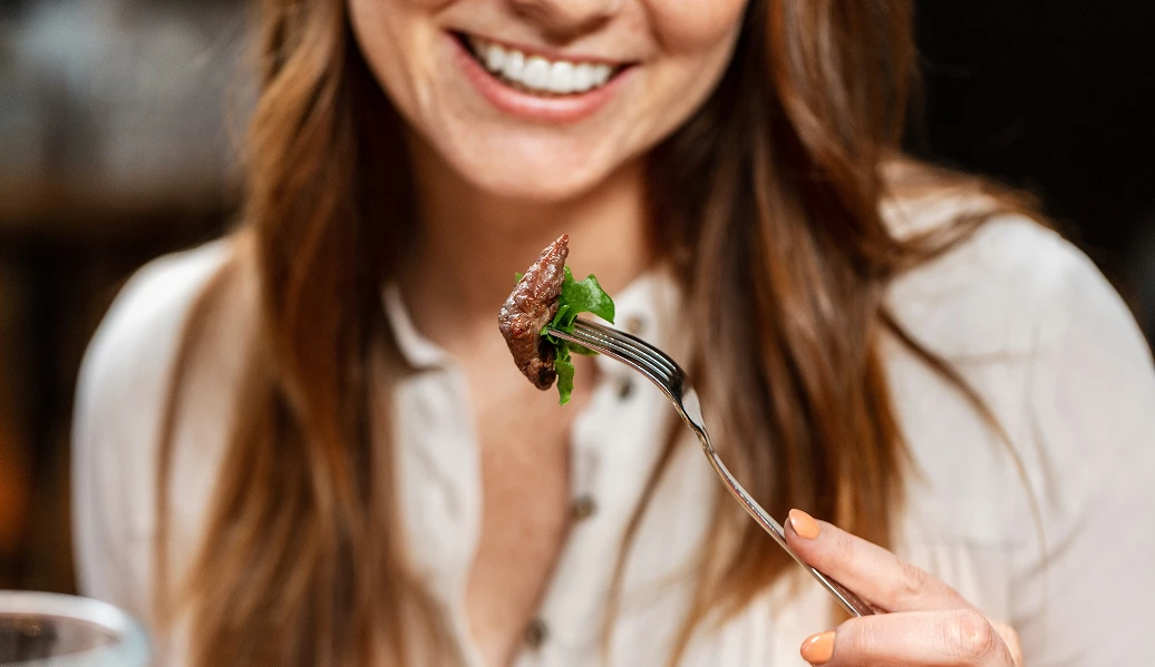 Pessoa segurando um garfo com carne