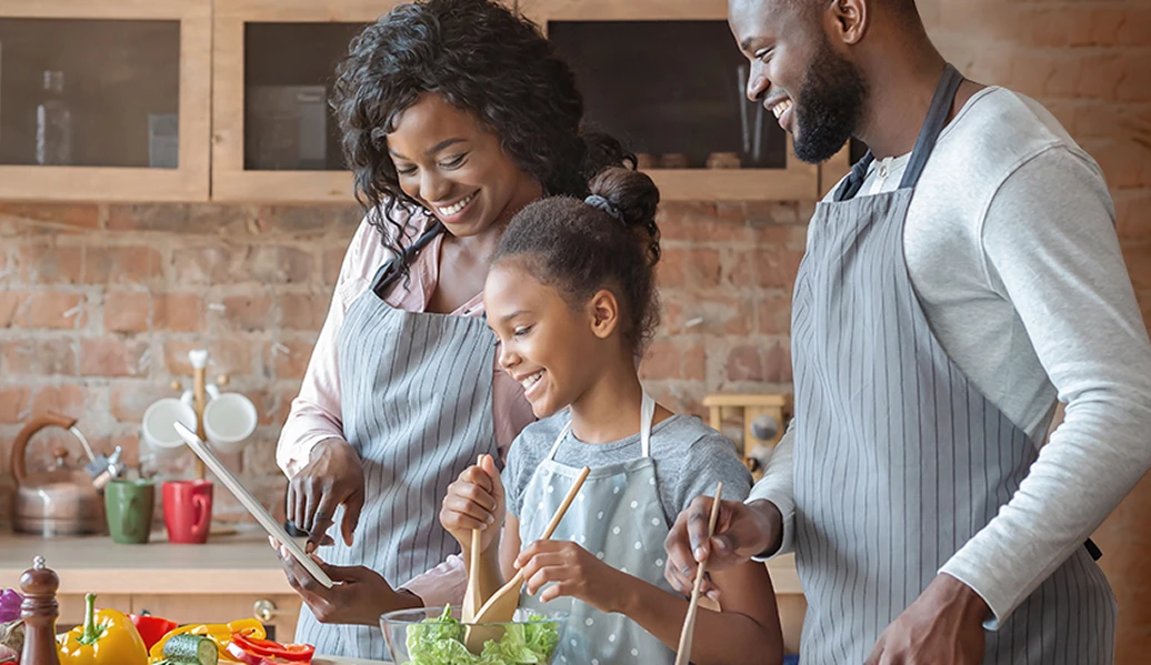 Pai e mãe cozinhando com a filha